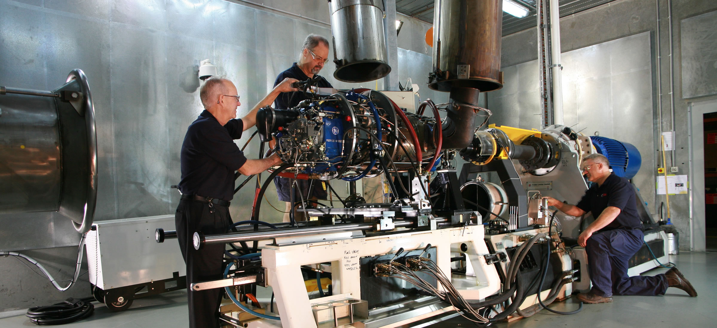Three men prepare H80 engine for test cell.